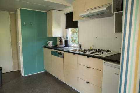 Moderne kitchenette in de Sun Lodge op Camping Les Bouleaux in Frankrijk, met fornuis en koelkast.
