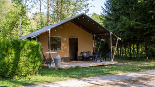 Safaritent bij Camping Les Bouleaux in Frankrijk, met terrasstoelen en groene, bosrijke omgeving.