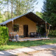 Tienda safari en Camping Les Bouleaux en Francia, con terraza y sillas, rodeada de naturaleza verde.