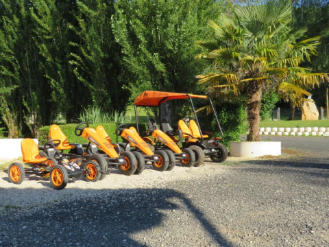 Verschillende oranje trapkarts en een familiefiets met zonnedak staan geparkeerd bij Camping la Salvinie, Frankrijk.
