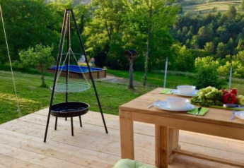 Terrasse en bois avec table à manger et barbecue, vue sur la verdure au Safari tent Camping Sretanwolf, Croatie.