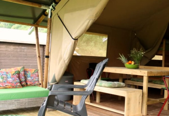 Safaritent met houten meubels en kleurrijke kussens bij Camping Sretanwolf in Kroatië, gedeeltelijk open.