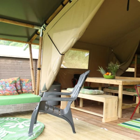 Tienda safari con muebles de madera y cojines coloridos en Camping Sretanwolf, Croacia, parcialmente abierta.