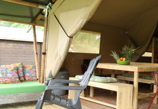Tienda safari con muebles de madera y cojines coloridos en Camping Sretanwolf, Croacia, parcialmente abierta.