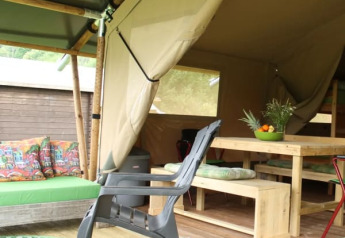 Tienda safari con muebles de madera y cojines coloridos en Camping Sretanwolf, Croacia, parcialmente abierta.