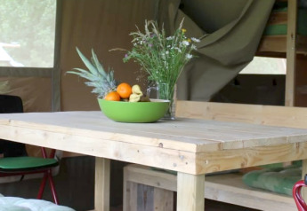 Houten tafel met fruitschaal en wilde bloemen in Safari tent + sanitary bij Camping Sretanwolf, Kroatië.