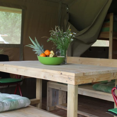 Houten tafel met fruitschaal en wilde bloemen in Safari tent + sanitary bij Camping Sretanwolf, Kroatië.