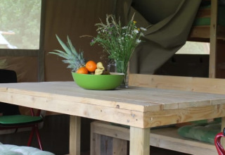 Træbord med frugtskål og vilde blomster i safariteltet Safari tent + sanitary på Camping Sretanwolf, Kroatien.