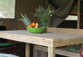 Mesa de madera con frutero y flores silvestres en la tienda Safari tent + sanitary de Camping Sretanwolf, Croacia.