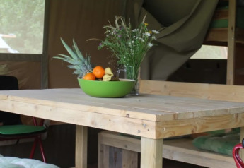 Houten tafel met fruitschaal en wilde bloemen in Safari tent + sanitary bij Camping Sretanwolf, Kroatië.