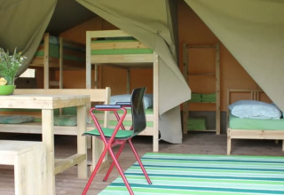 Interno di tenda safari con letti a castello e tavolo da pranzo al Camping Sretanwolf in Croazia.