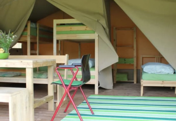 Interno di tenda safari con letti a castello e tavolo da pranzo al Camping Sretanwolf in Croazia.