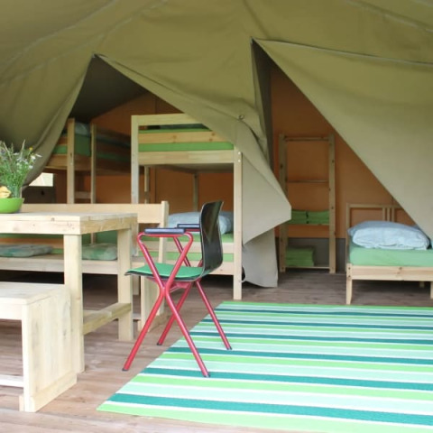 Interno di tenda safari con letti a castello e tavolo da pranzo al Camping Sretanwolf in Croazia.