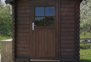 Træhytte med halv dør og vindue foran Safari tent + sanitary på Camping Sretanwolf i Kroatien i solskin.