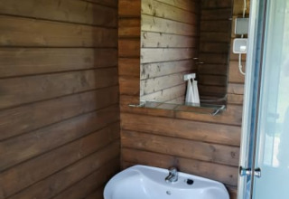 Wastafel met spiegel en lamp in houten badkamer van Safari tent + sanitary op Camping Sretanwolf, Kroatië.