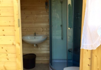 Wooden bathroom with shower, sink, and toilet inside a safari tent at Camping Sretanwolf in Croatia.