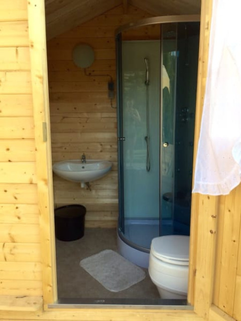Houten badkamer met douche, wastafel en toilet in een safaritent bij Camping Sretanwolf in Kroatië.