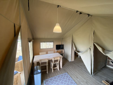 Interior de una tienda safari con mesa de comedor en Camping Jagtveld, Países Bajos.