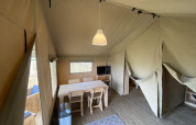 Intérieur d'une tente safari avec table et chaises au Camping Jagtveld aux Pays-Bas.