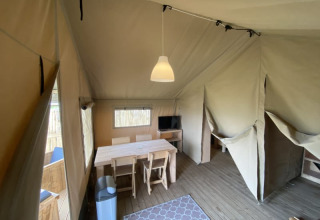 Interior of a safari tent with dining table and chairs at Camping Jagtveld in the Netherlands.