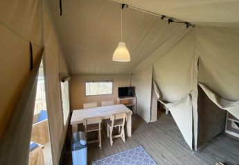Interior de una tienda safari con mesa de comedor en Camping Jagtveld, Países Bajos.