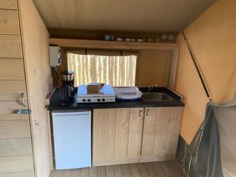 Keukenhoek in de Safari tent + toilet bij Camping Jagtveld in Nederland, met fornuis en spoelbak.