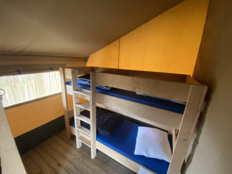 Interieur van een safaritent met stapelbedden en houten vloer bij Camping Jagtveld in Nederland.