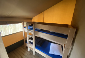 Interior de una tienda safari con literas y suelo de madera en Camping Jagtveld, Países Bajos.