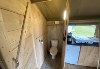 Binnenzicht van een safaritent met toilet en keukentje op Camping Jagtveld in Nederland.