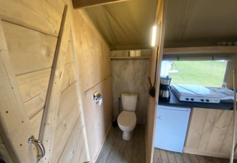 Vista interna di una tenda safari con bagno e angolo cottura al Camping Jagtveld nei Paesi Bassi.