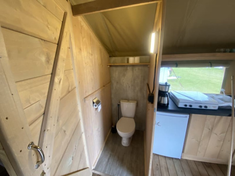 Vista interna di una tenda safari con bagno e angolo cottura al Camping Jagtveld nei Paesi Bassi.