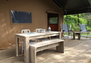 Outdoor-Terrasse eines Safarizelts mit Holztisch, Bank und Stühlen bei Tenuta Tredici Ulivi in Italien.