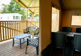 Interno ed esterno di tenda safari con terrazza e sedie a Camping Tussen de Diepen, Paesi Bassi.