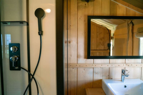 Badezimmer eines Safari-Zeltes mit Dusche, Spiegel und Waschbecken auf Camping Tussen de Diepen, Niederlande.
