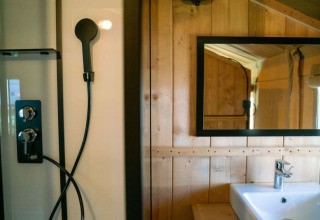 Salle de bain dans une tente safari avec douche, miroir et lavabo au Camping Tussen de Diepen aux Pays-Bas.