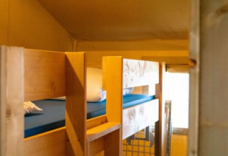 Binnenzicht van een safaritent met houten stapelbedden bij Camping Tussen de Diepen, Nederland.