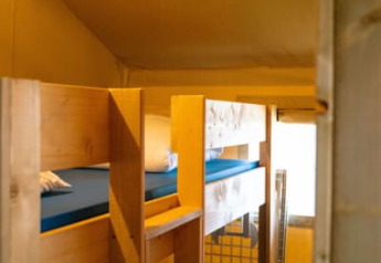 Interno di una tenda safari con letti a castello in legno al Camping Tussen de Diepen, Paesi Bassi.