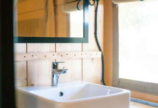 Moderne wastafel en spiegel in een safaritent met sanitair op Camping Tussen de Diepen in Nederland.