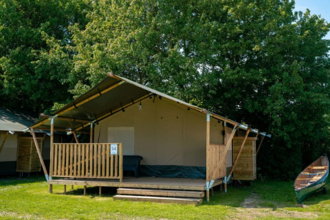 Tente safari avec terrasse et sanitaires au Camping Tussen de Diepen, Pays-Bas, entourée d’arbres.