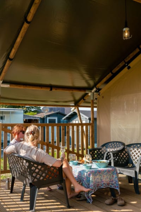 Due persone si rilassano nella tenda safari con servizi privati a Camping Tussen de Diepen, Paesi Bassi.