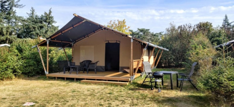 Safari tent at Ballum Camping in Denmark with deck, outdoor seating and barbecue in natural setting.