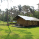 Safari-telt med sanitære faciliteter og rutsjebane på Familiepark Goolderheide, Belgien, omgivet af træer.