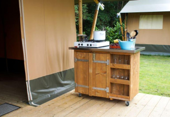 Outdoor kitchenette on a wooden deck outside a safari tent at Camping de Breede, Netherlands, with stove.