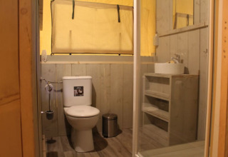 Baño dentro de la Safari tent + sanitary en Familiepark Goolderheide, Bélgica, con inodoro y lavabo visibles.