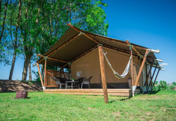 Safari-Zelt mit Sanitäranlage auf Camping de Tolbrug in den Niederlanden, umgeben von Bäumen und Gras.