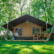 Udendørsbillede af Lodge Compact ved Camping de Tolbrug i Holland omgivet af grønne træer og græs.