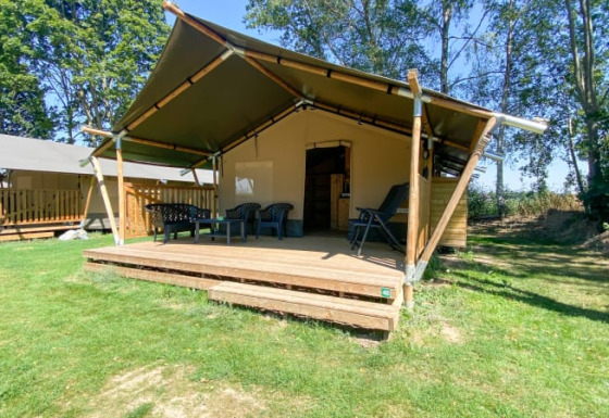 Tenda safari con veranda e sedie esterne presso Camping de Tolbrug, circondata da prato e alberi nei Paesi Bassi.