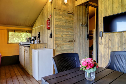 Binnenaanzicht van safaritent met eigen sanitair bij Camping Dal van de Mosbeek, met keukentje en tv.