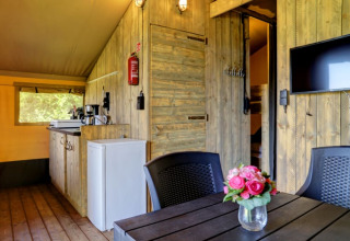 Vista interna della tenda Safari con bagno privato al Camping Dal van de Mosbeek, angolo cottura e TV.