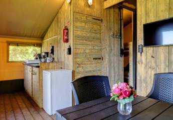 Vista interna della tenda Safari con bagno privato al Camping Dal van de Mosbeek, angolo cottura e TV.